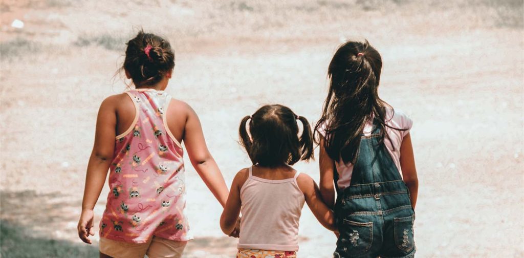 three young girls are holding hand