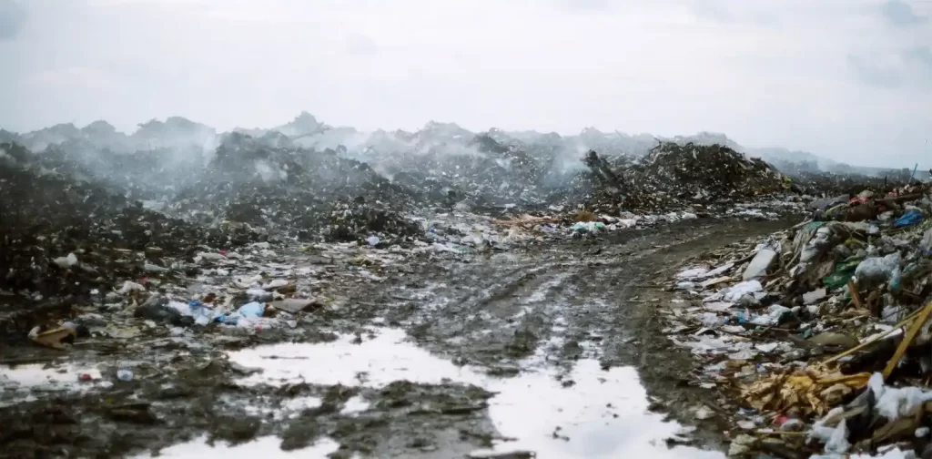 a muddy road with mountains of Thilafushi island's trash on the background