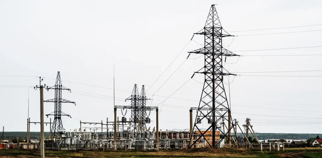 three electric towers standing against the white sky