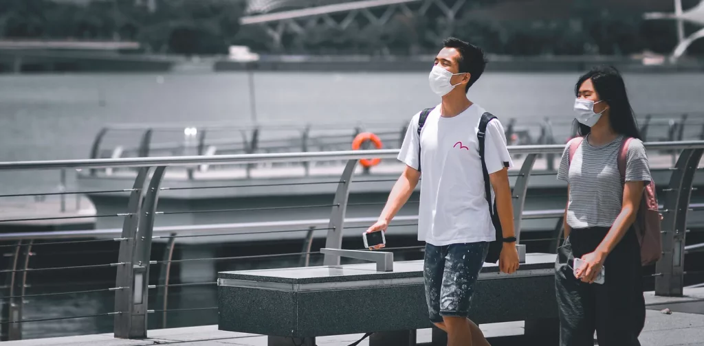 Men and woman wearing mask walk together in street