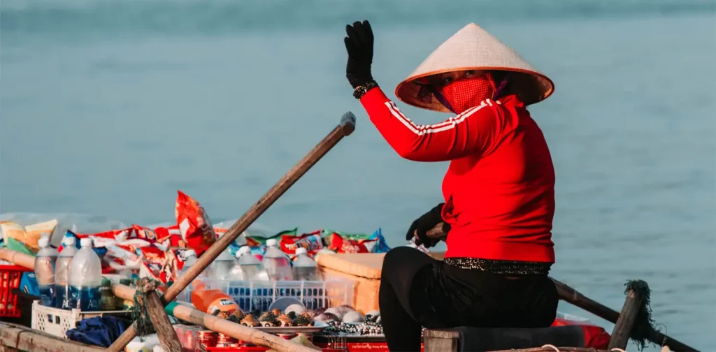 a snack seller on a boat wearing a hat