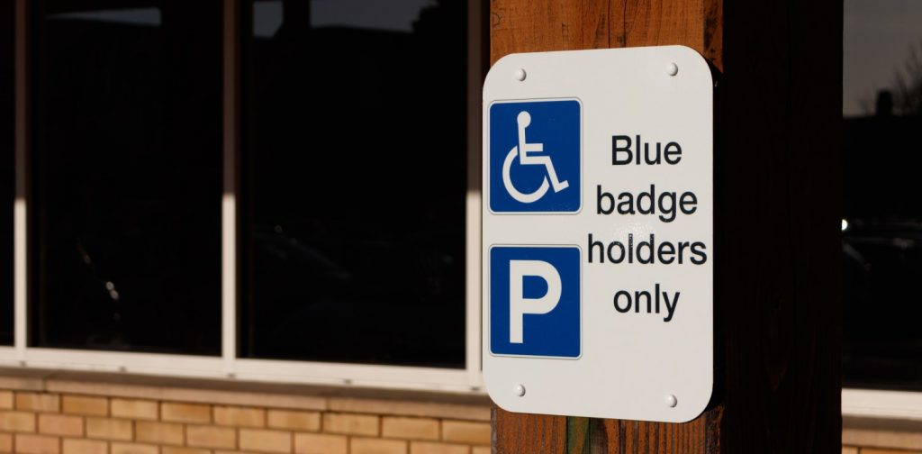 a blue parking sign that reads “Blue badge holders only” indicating designated space for people with disabilities