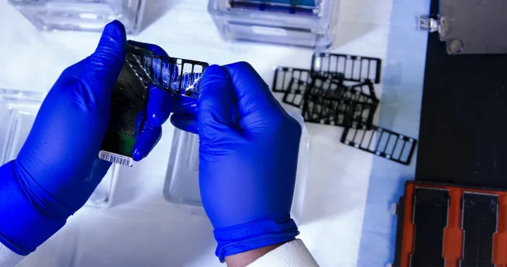 hands covered in blue gloves working with tools in the lab